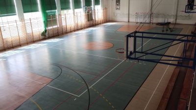 Sala gimnastyczna z boiskiem do koszykówki i siatką.